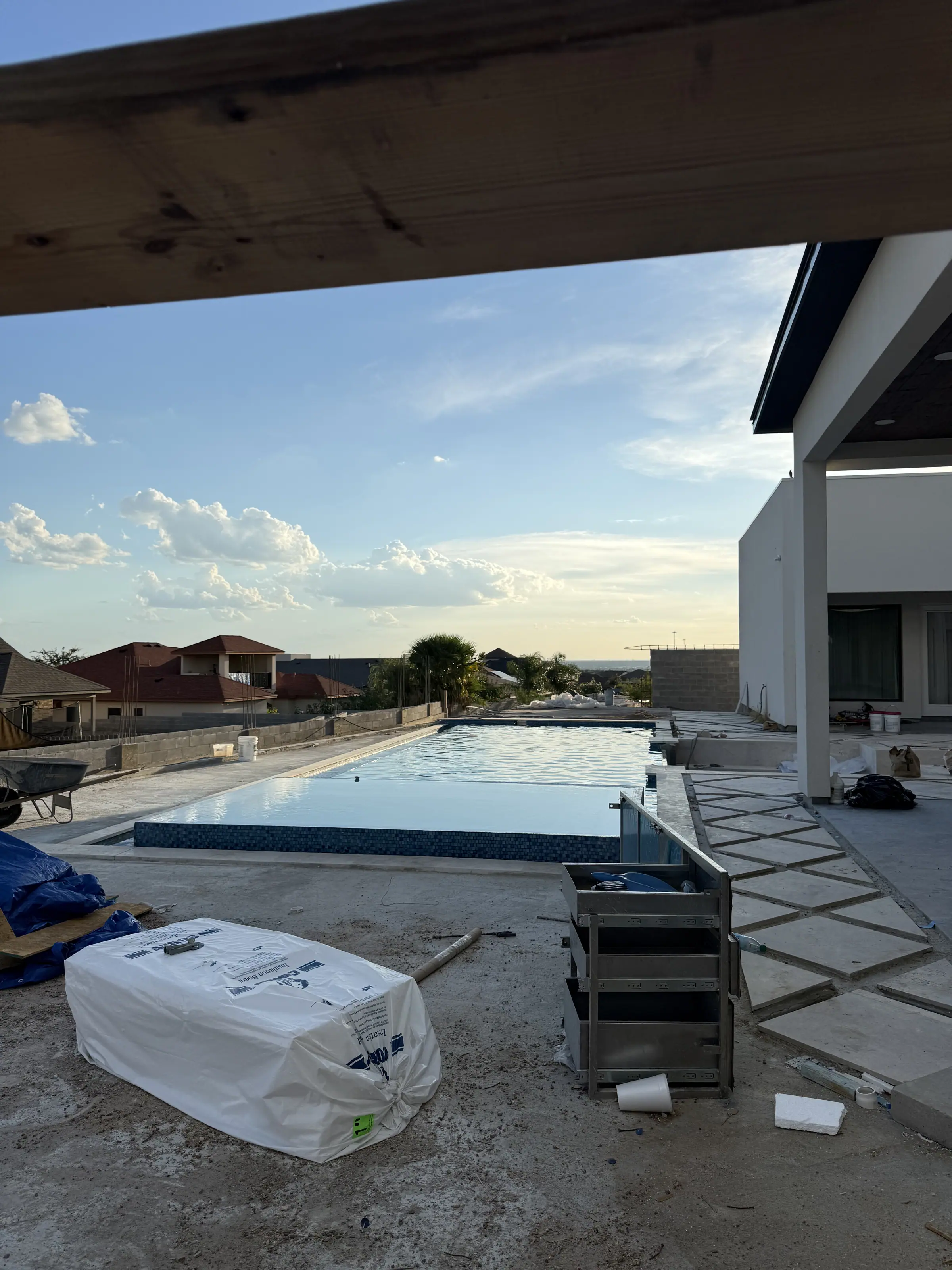 Pool and surrounding deck under construction behind a new Laredo home at dusk