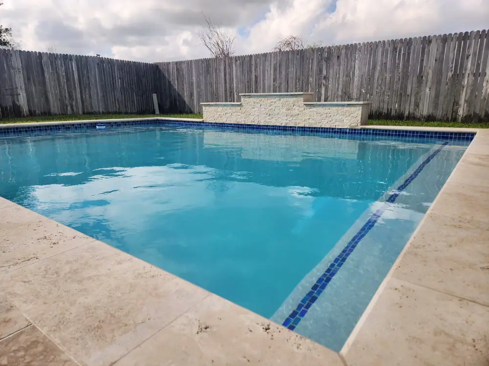 Rectangular JCW pool with a dark waterline tile band and a wide stamped-concrete deck