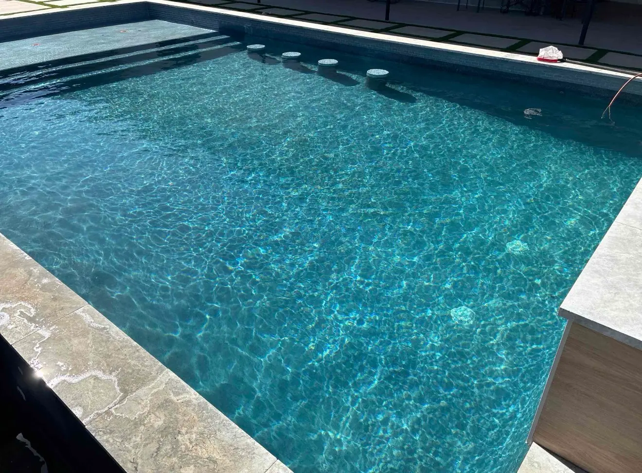 Clear water over a dark interior finish in a JCW pool, sunlight moving across the surface