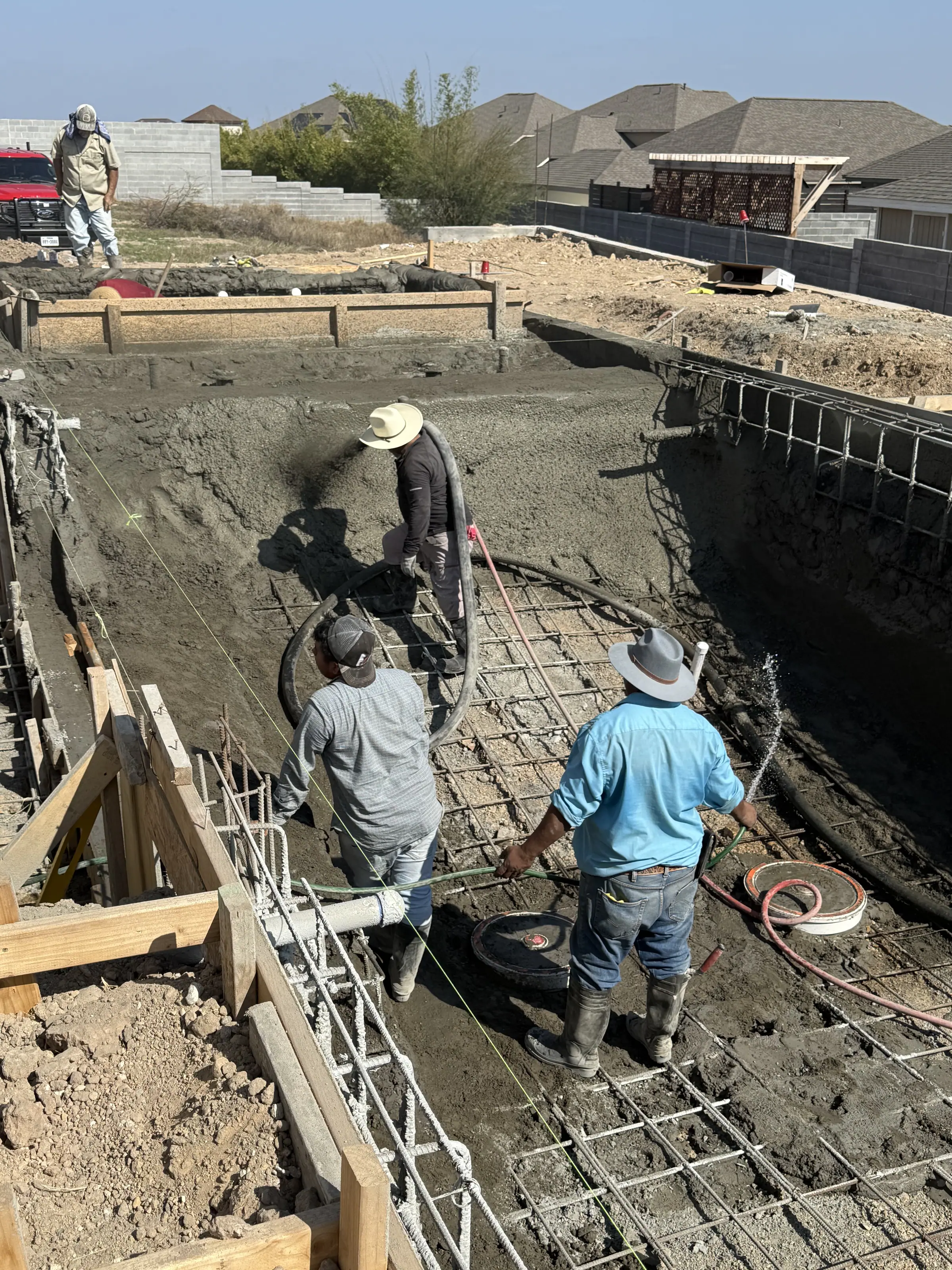 JCW Pools crew tying steel reinforcement inside an excavated pool shell in a Laredo backyard