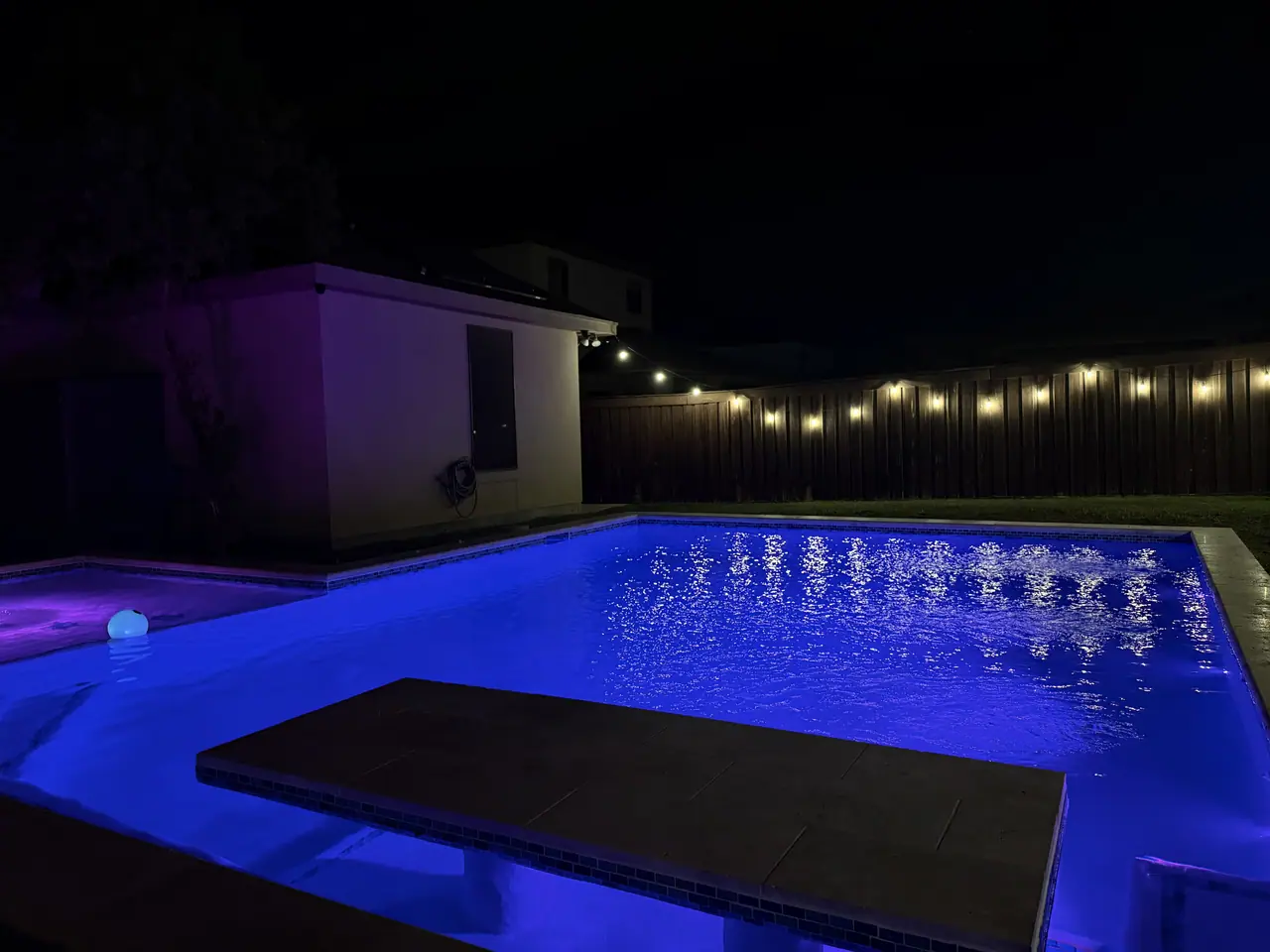 JCW pool lit blue and violet at night with a raised wall and sheer descent spillway